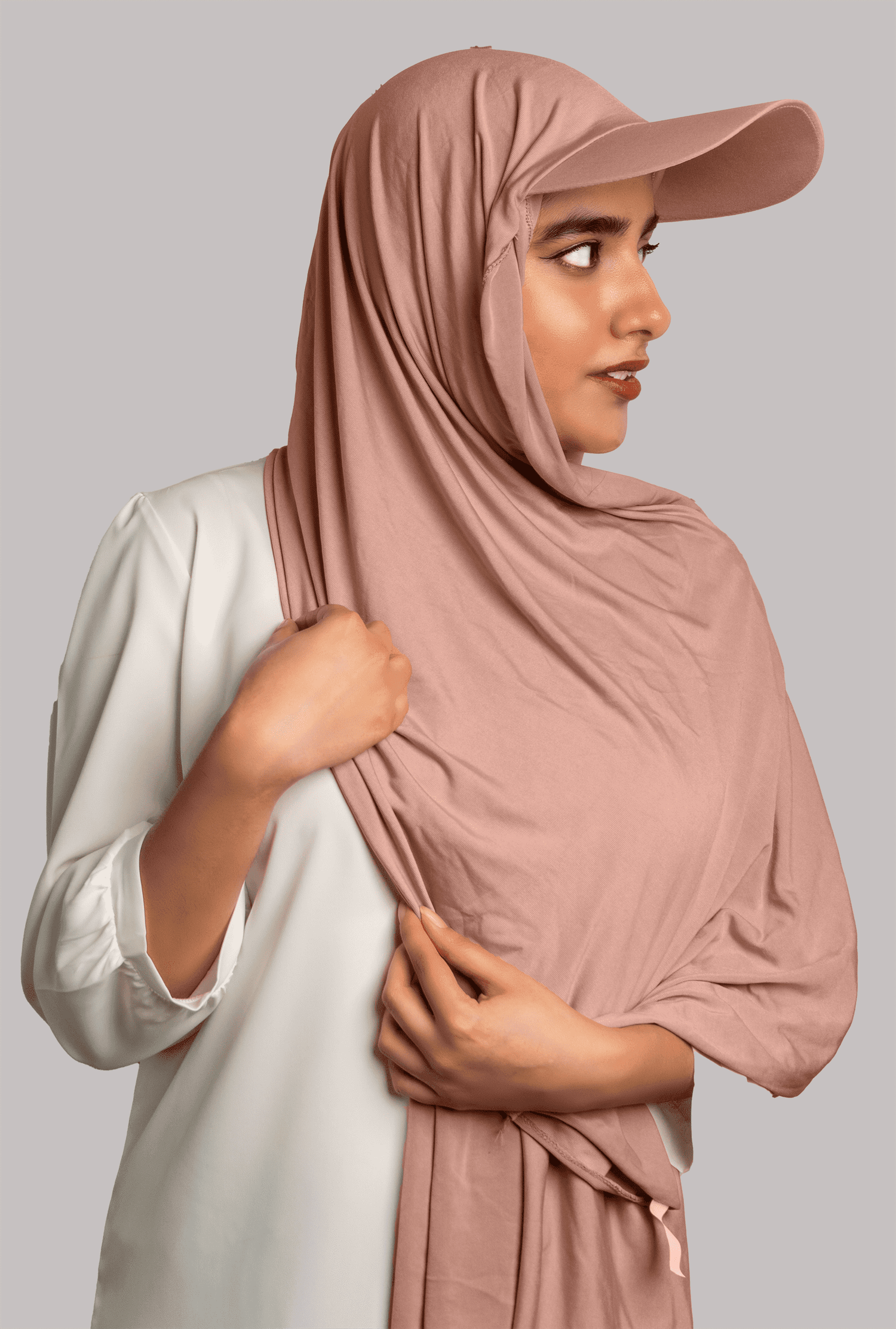 Girl Wearing Stylish Hat Hijab in meat pink color. looking left.