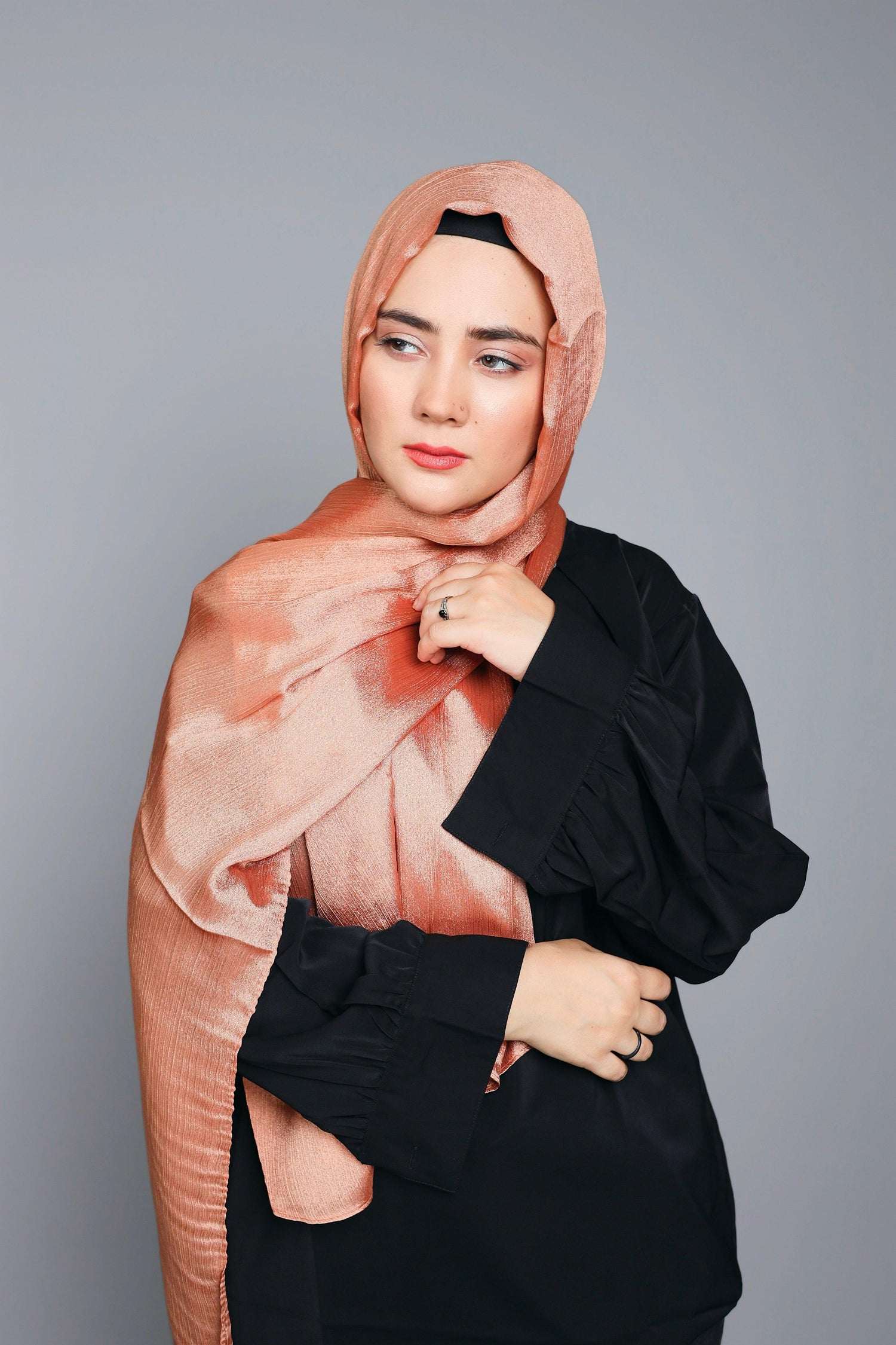 Woman styling Metallic Chiffon Hijab in Stunning Copper shade over black top.