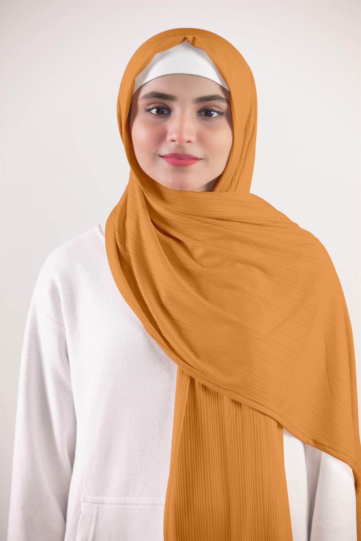 Ribbed Jersey Hijab in Mustard Individual wearing it over a white top for a fashionable look.