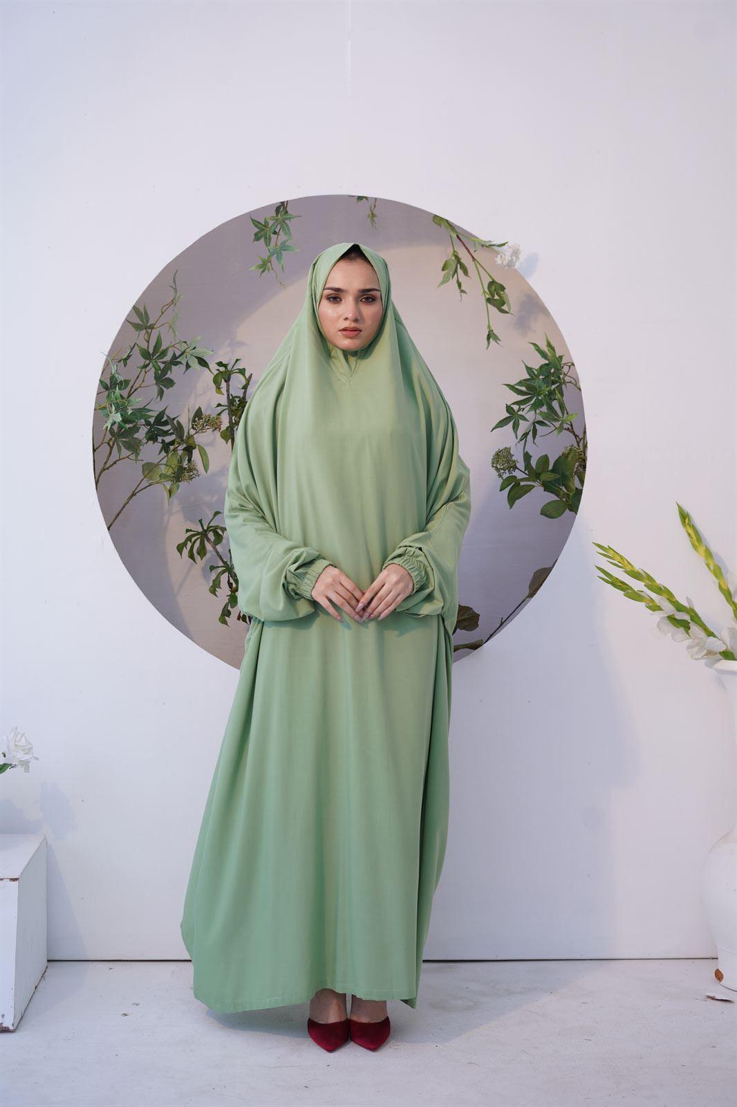 A lady wearing salah prayer chadar in green color.