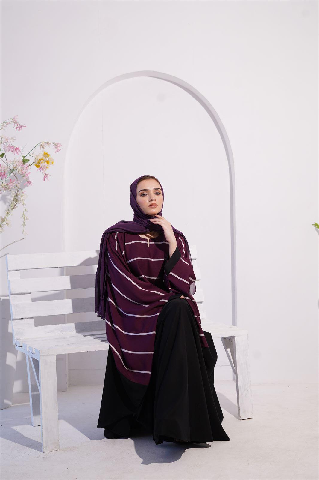 Zoom line jilbab abaya for women in eggplant color. girl sitting on bench wearing it.