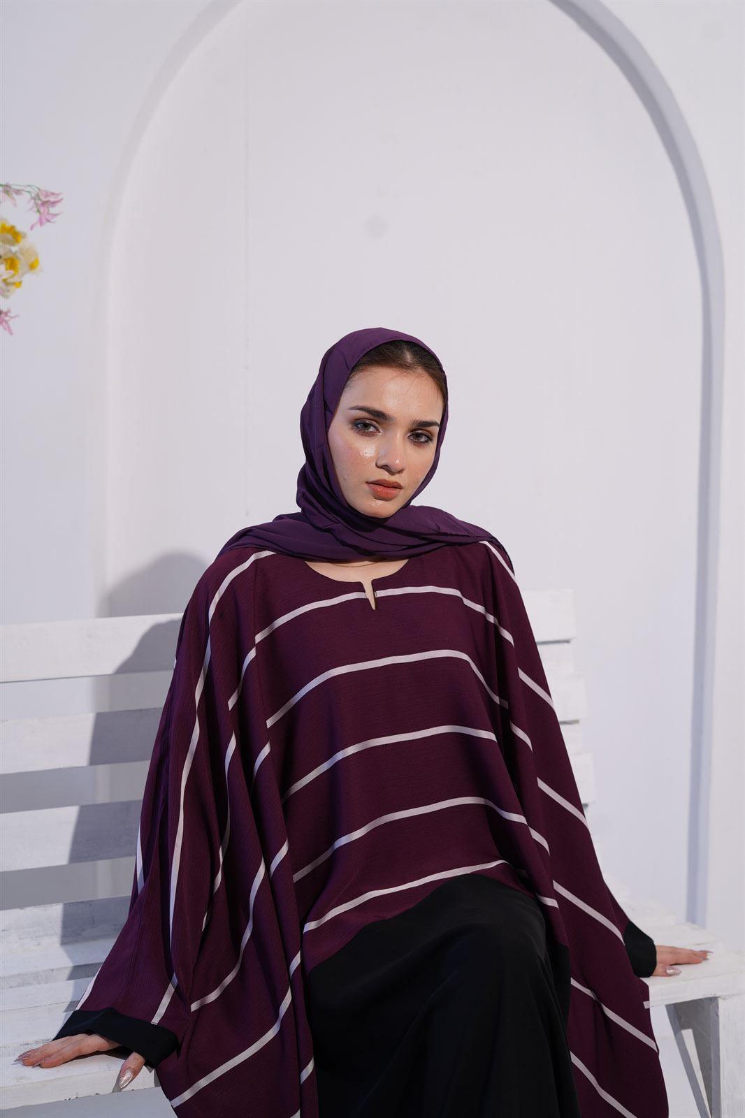 Zoom line jilbab abaya for women in eggplant color. closeup of girl on bench wearing it.