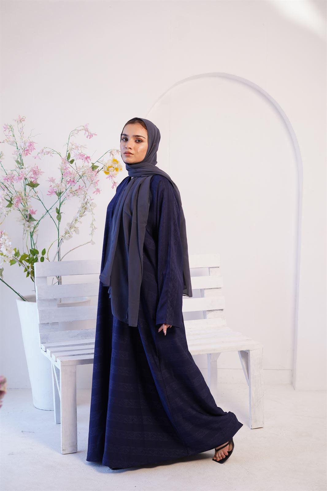 Girl Wearing Zoom Emboss navy blue Gown design abaya, standing beside a bench.
