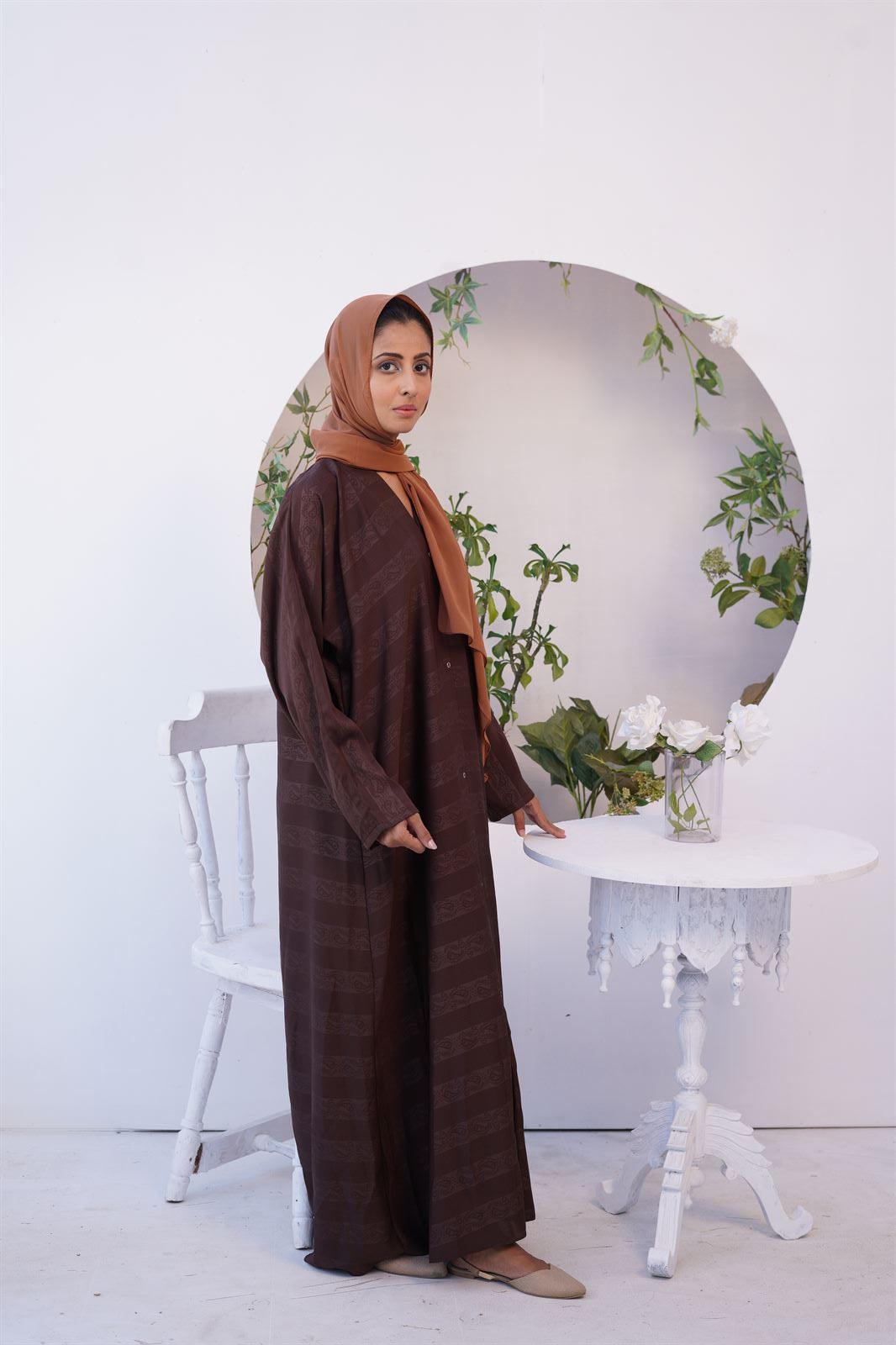 Girl Standing in one of zoom emboss Gown Premium Abayas.