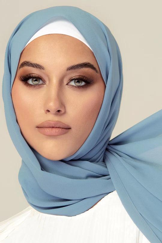 Georgette Hijab in sapphire color. girl wearing it on white top looking her straight.