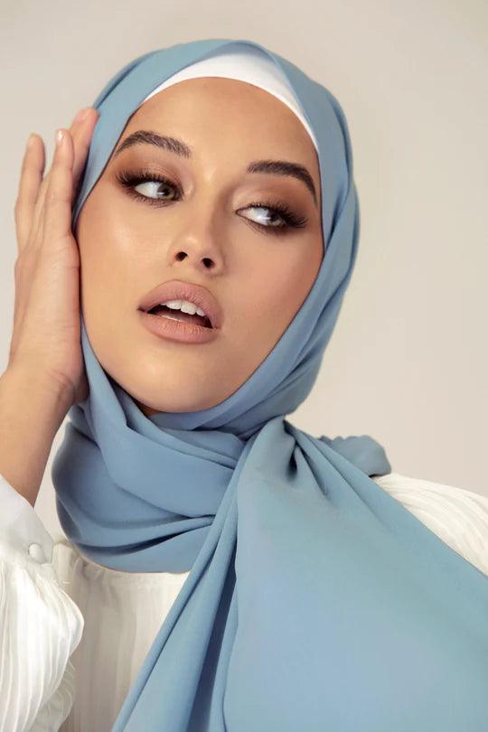 Georgette Hijab Online Pakistan, in sapphire color . a stylish hijabi draping it over a white top looking her left