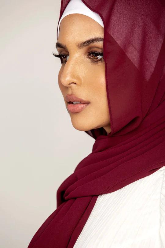 Georgette Hijab Online Pakistan, in burgundy color . a women wearing it with white top looking her right.