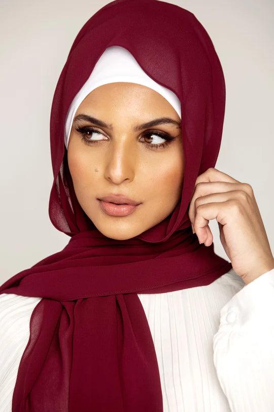 Georgette Hijab Online Pakistan, in burgundy color . a women wearing it with white top looking her right.