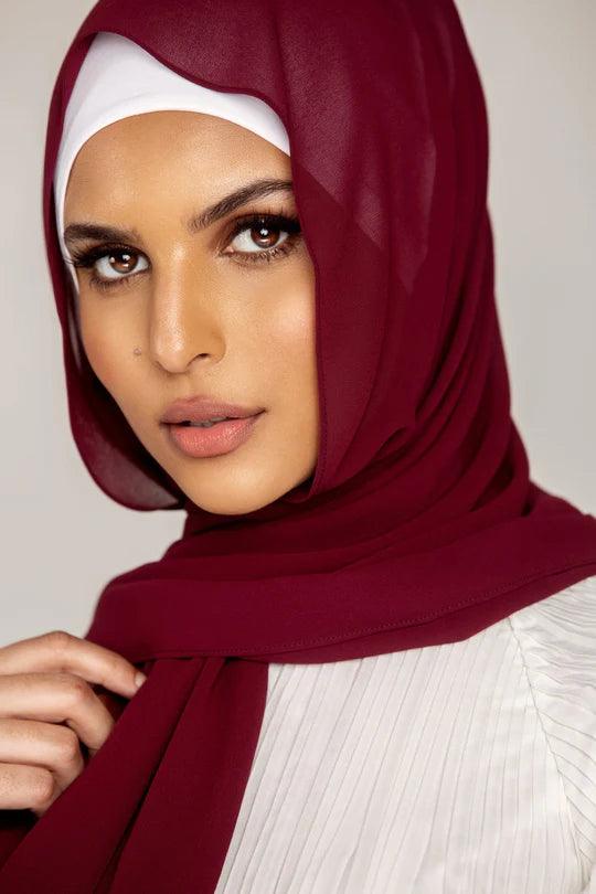 Georgette Hijab Online Pakistan, in burgundy color . a women wearing it with white top looking her straight.