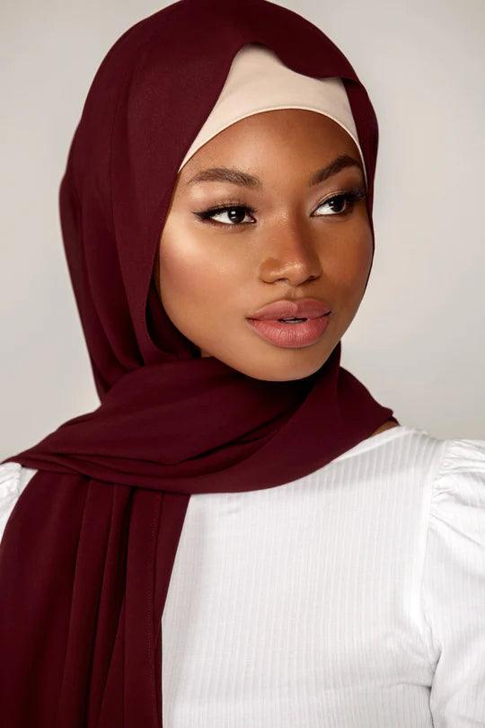 Georgette Hijab Online Pakistan, in brick color . a woman wearing it with white top looking her left.