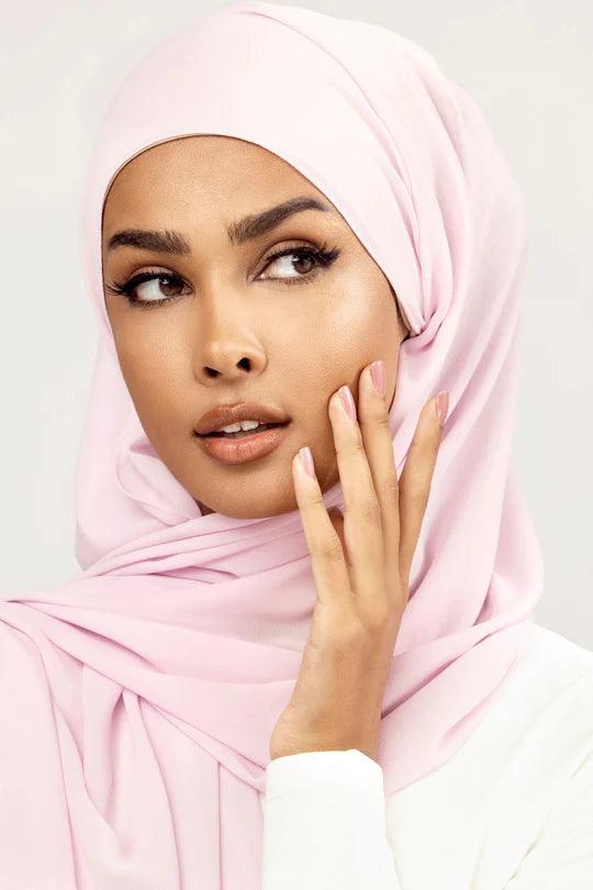 Georgette Hijab Online Pakistan, in baby pink color. A woman wearing it with white top looking her left.