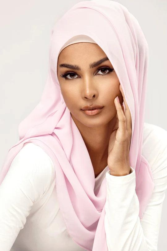 Georgette Hijab Online Pakistan, in baby pink color. A woman wearing it with white top looking her straight.