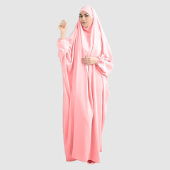 A woman wearing a pure Namaz Chadar in baby pink color is looking straight.