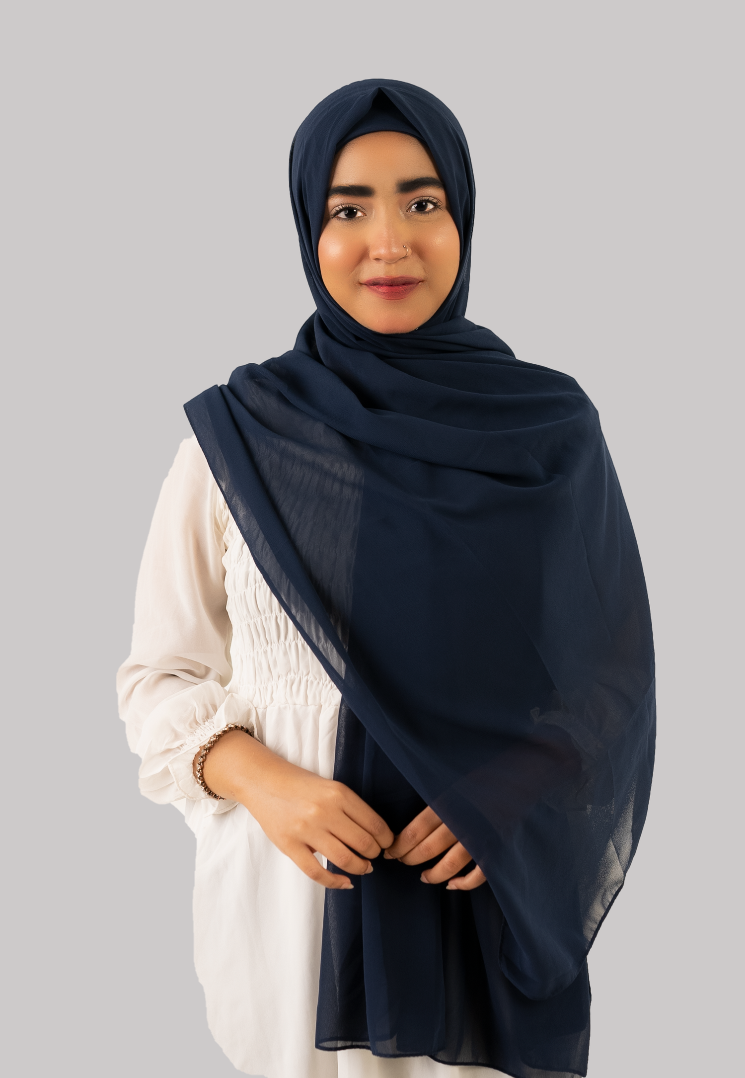 A woman elegantly styles a navy georgette instant hijab with cap looking front.