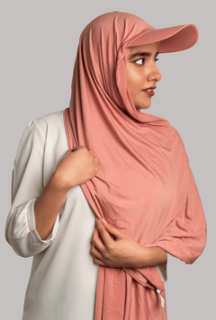 A women wearing a stylish Hat Hijab in pink color and a white top looking to her left