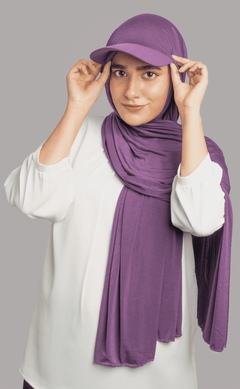 A women wearing a stylish Hat Hijab in purple color and a white top looking to her sraight