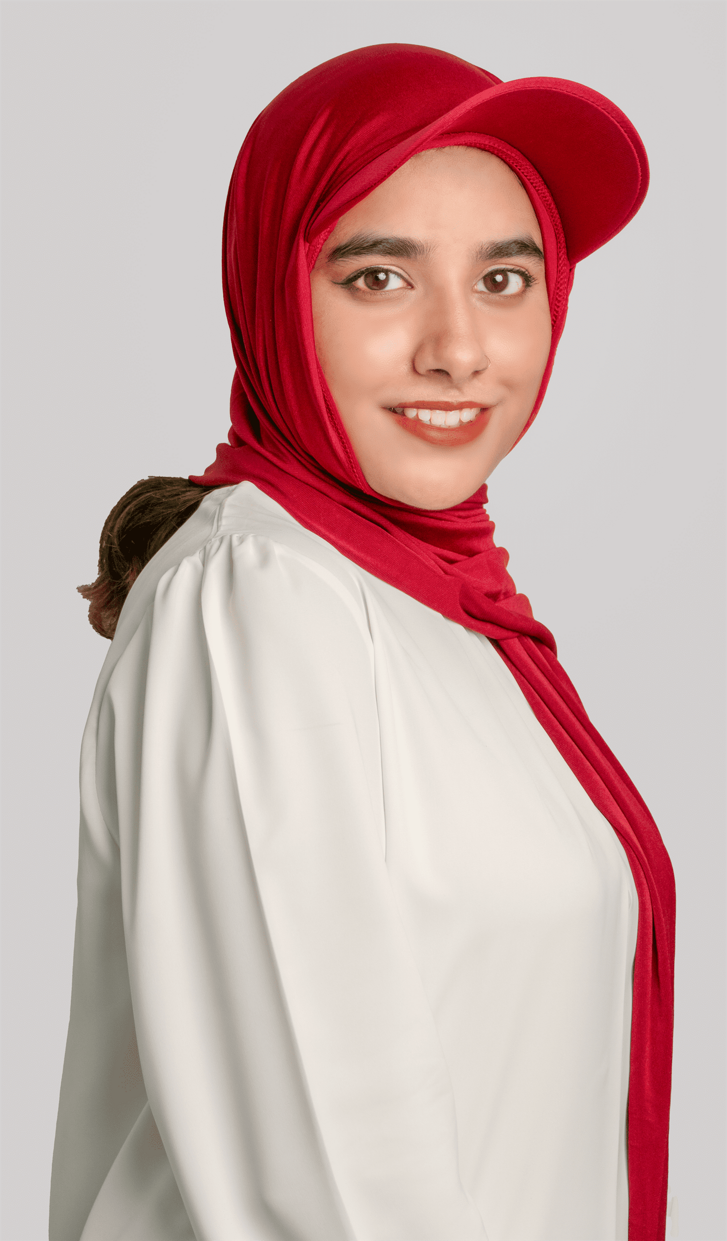 A women wearing a stylish Hat Hijab in maroon color and a white top looking to her straight side profile