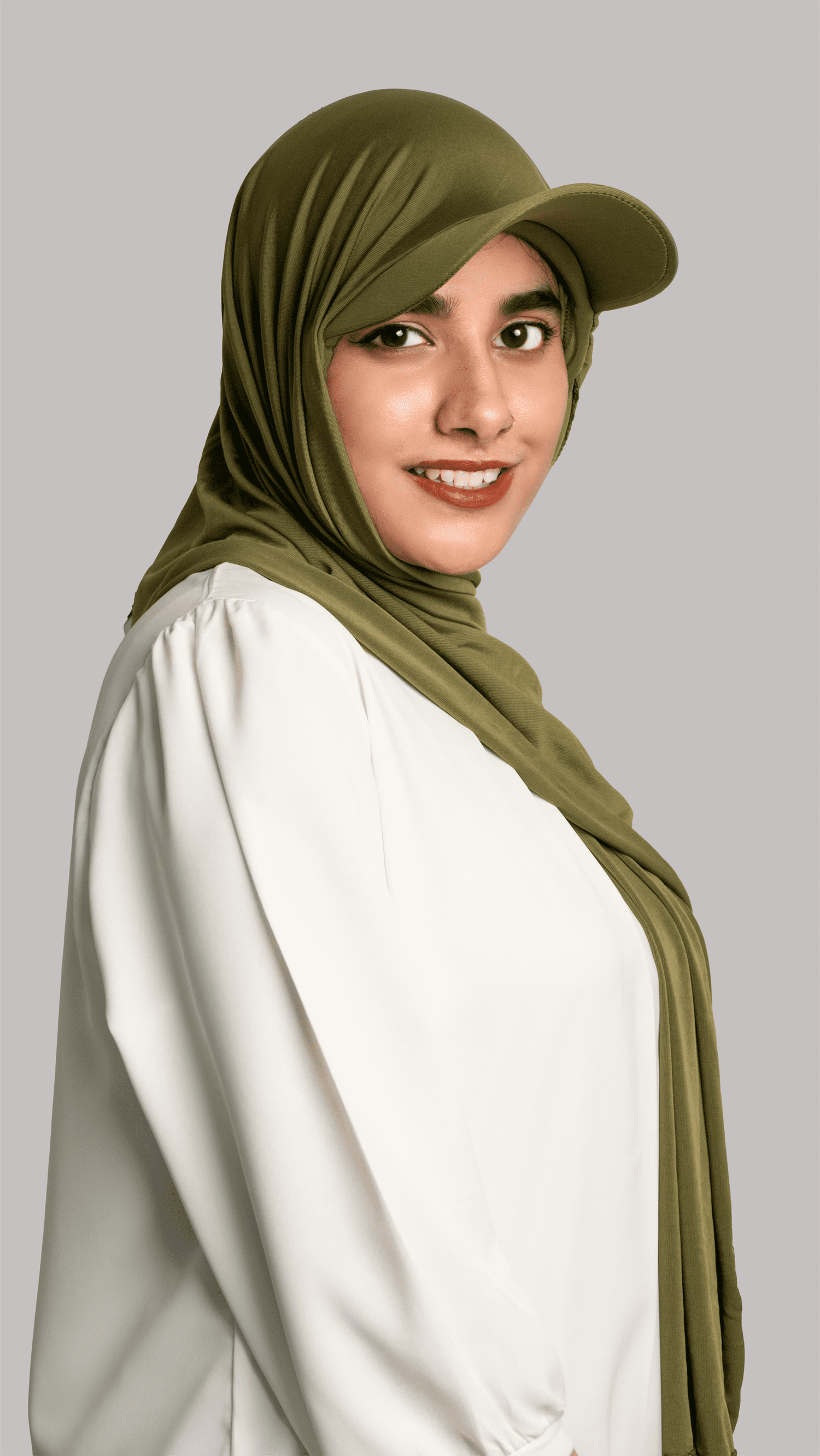 A women wearing a stylish Hat Hijab in olive green color and a white top looking to her straight side profile