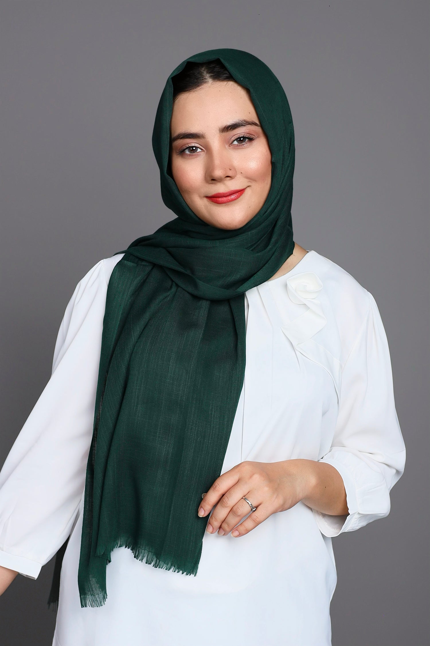 A women wearing Turkish Hijab, viscose fabric, in bottle green colour, with white top looking her straight