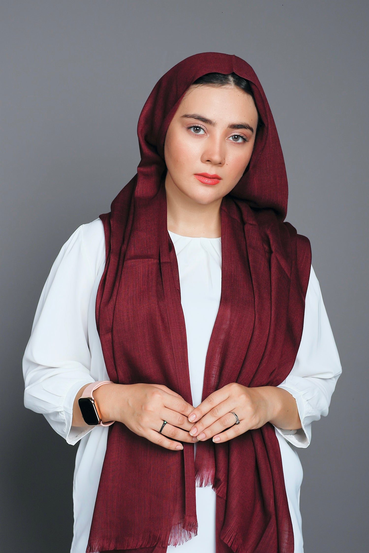 Girl wearing Turkish Hijab, viscose fabric, in burgundy color, with white top looking straight.