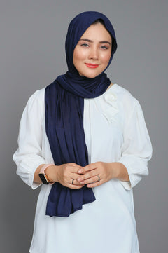 Girl wearing Jersey Hijab in pebble color over white top looking straight.