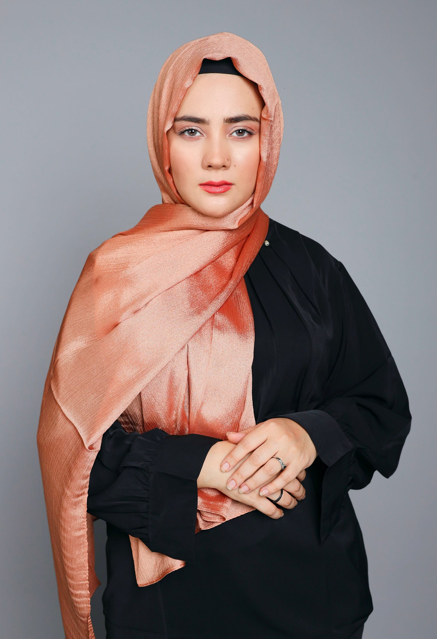 Metallic Chiffon Hijab in Copper shade. Woman styling it over black top.