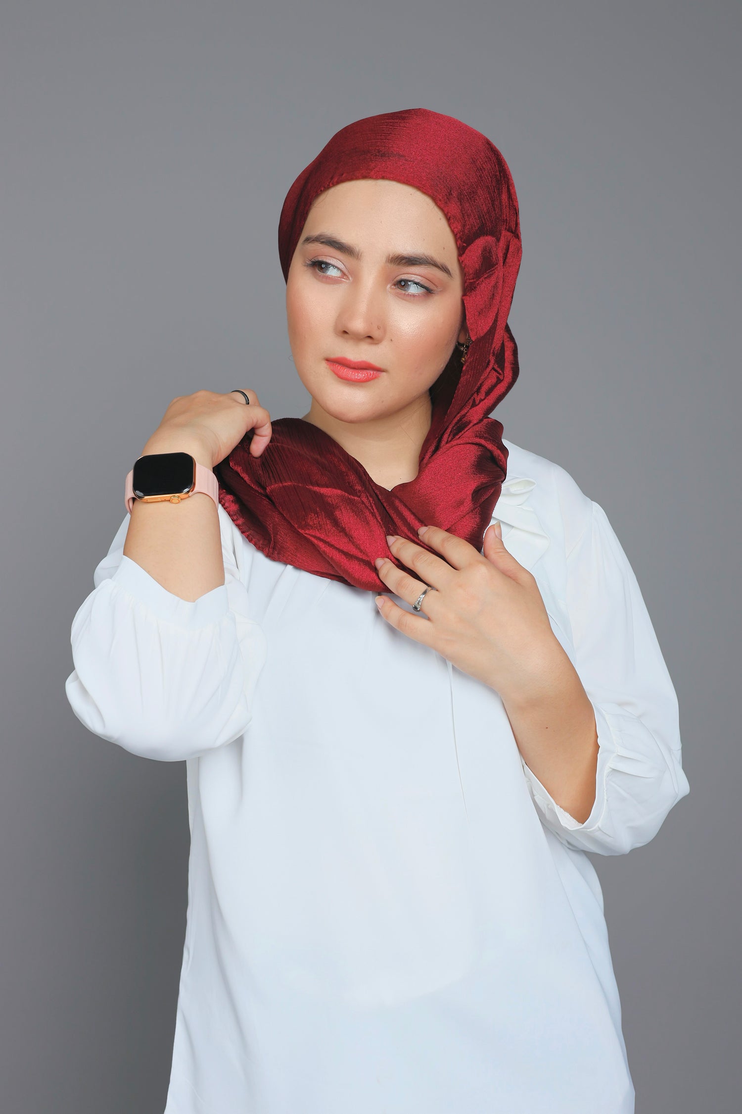 stylish hijabi wearing Metallic chiffon Hijab in maroon over white top looking right.