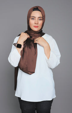 A woman styling in Metallic Chiffon Hijab in dark brown on a white top.