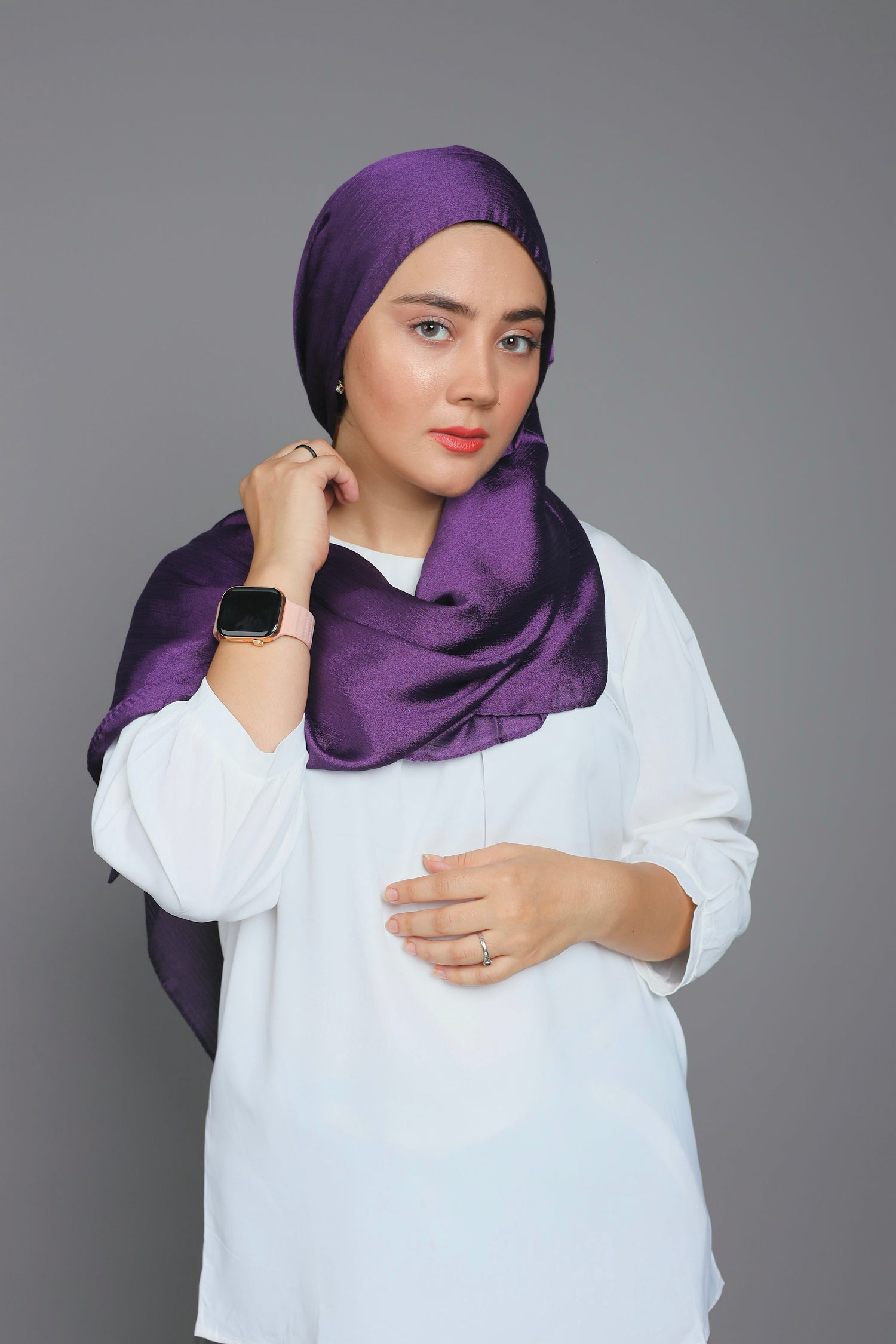 Woman draping Luxurious Metallic Chiffon Hijab in Dark Purple over white top.