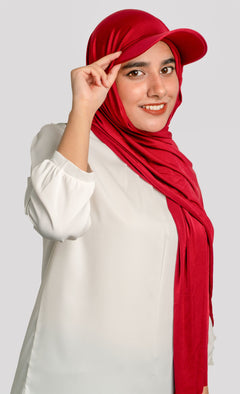 A women wearing a stylish Hat Hijab in maroon color and a white top looking to her straight