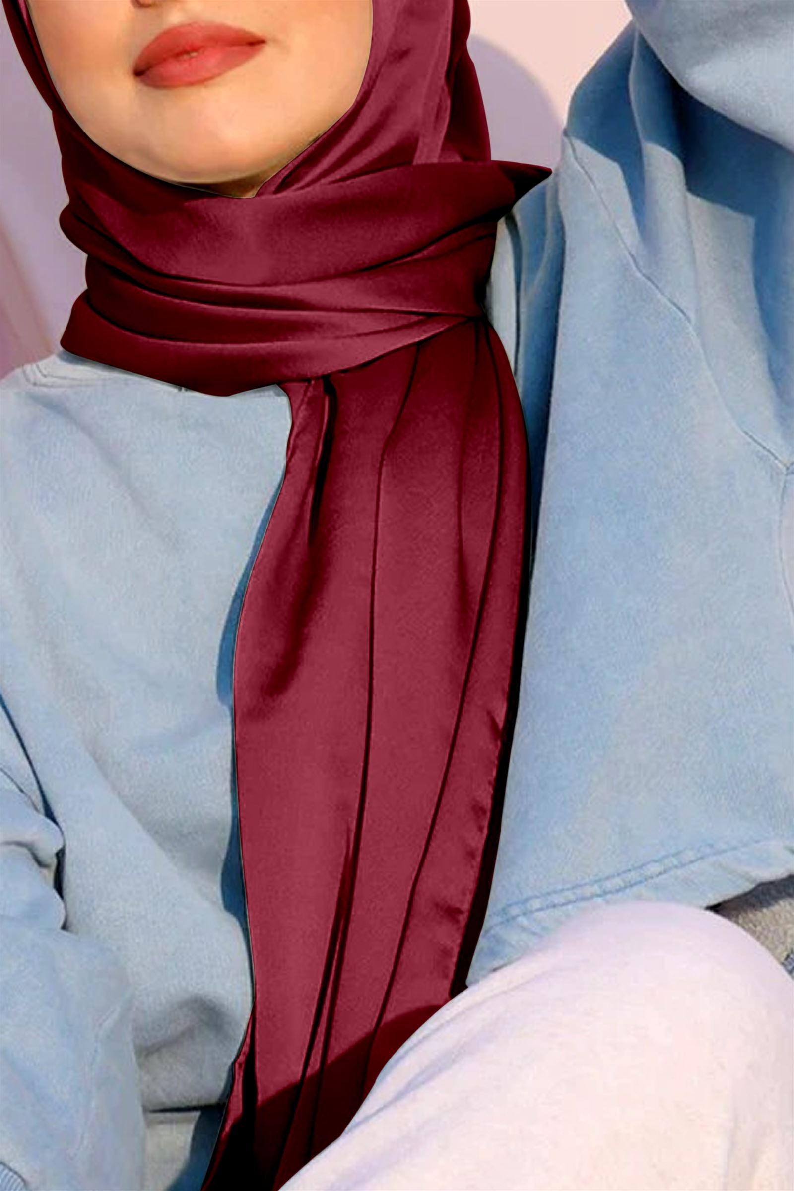 a lady with satin silk hijab on. maroon color.