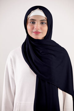 Ribbed Jersey Hijab in Navy Blue. Chic woman wearing it over a white top. Made from Premium Ribbed Jersey.