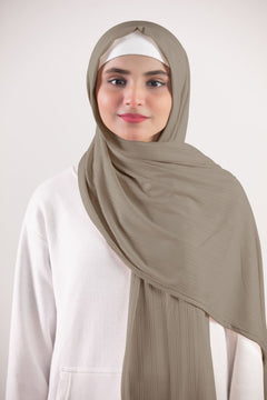 Ribbed Jersey Hijab in Oatmeal Individual draping it over white top for a chic appearance.