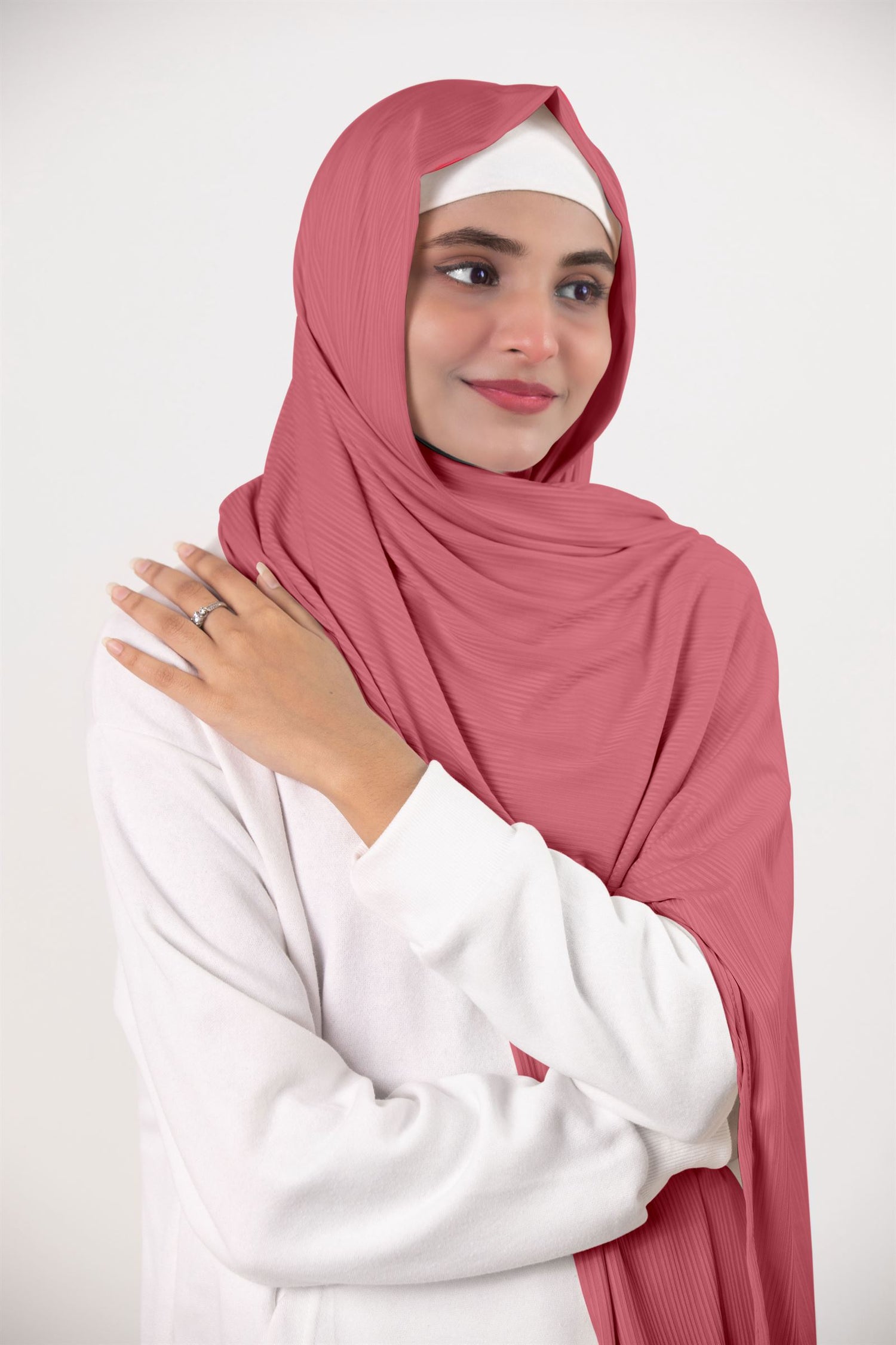 Ribbed Jersey Hijab in blossom. Fashion-forward hijabi draping it over a white top. Premium Ribbed Jersey Hijab.