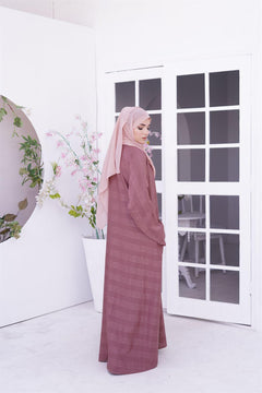 Girl wearing Zoom Embossed gown design abaya in coral shade. side view.