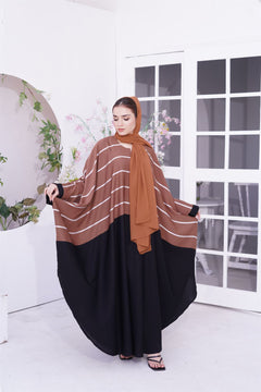 girl wearing a zoom line jilbab abaya design in light brown. looking downwards at right.