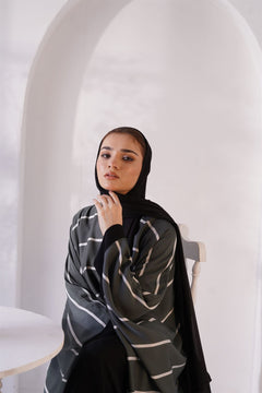 Closeup of a girl wearing zoom line abaya jilbab online sitting on chair.