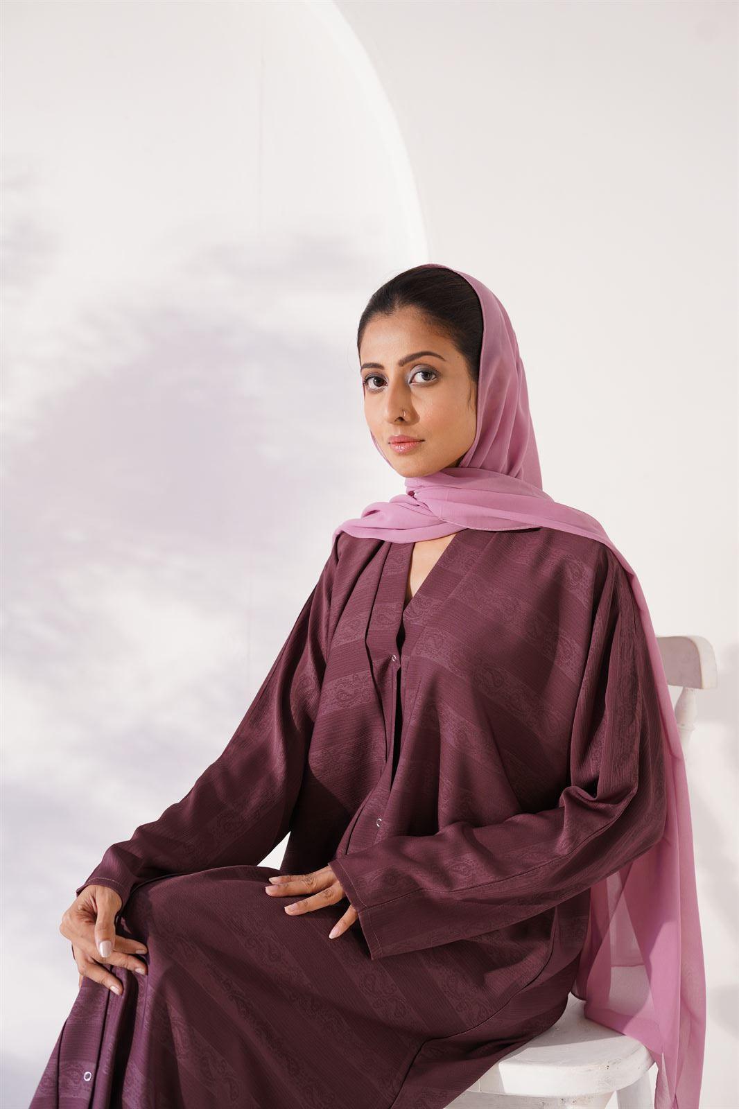 Girl Sitting and wearing Zoom emboss abaya gown style in grape.