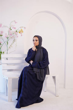 Girl Wearing Zoom Emboss navy blue Gown design abaya, sitting on a bench. 