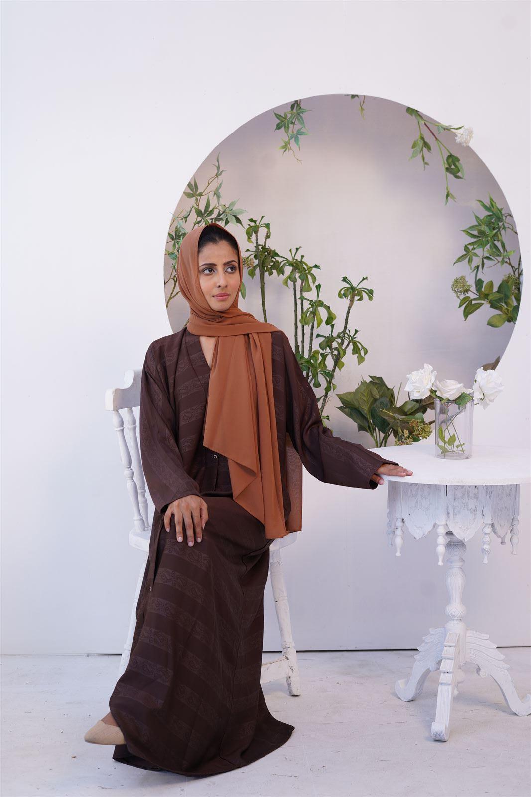 Girl Sitting wearing one of Premium Abayas. Zoom emboss gown  style.
