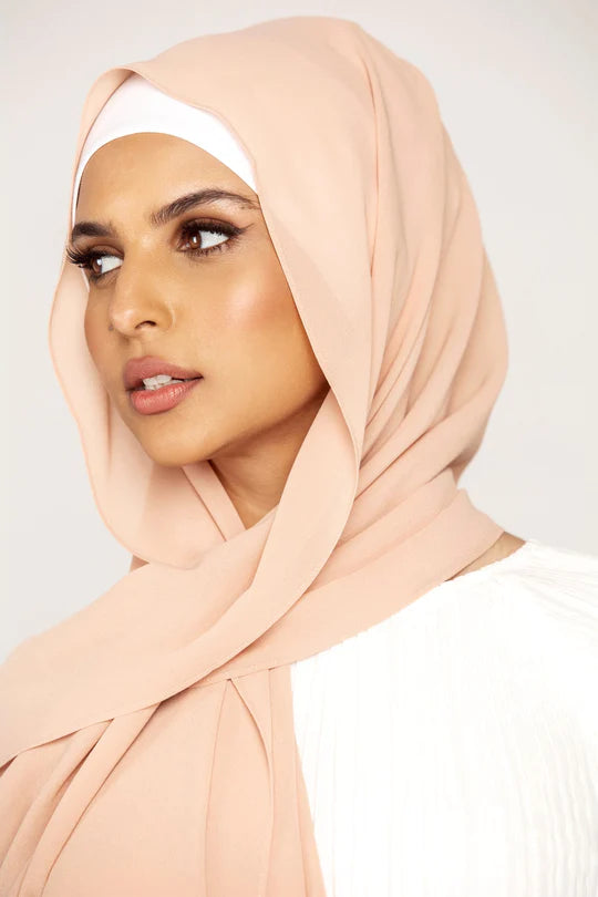 Georgette Hijab Online Pakistan, in nude color. A woman wearing it with white top looking her right.