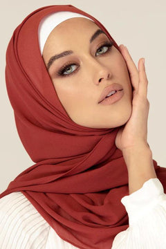 Georgette Hijab Online Pakistan, in brick color . a woman wearing it with white top looking her straight.