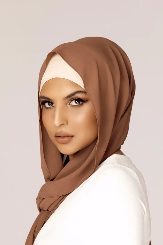 A women wearing Hijab in mocha color, with white top looking her straight