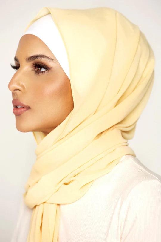 Georgette Hijab Online Pakistan, in pancake color. A woman wearing it with white top side profile.