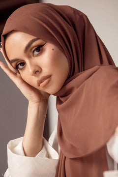 Georgette Hijab Online Pakistan, in cedar color . a women wearing it with white top looking her straight.