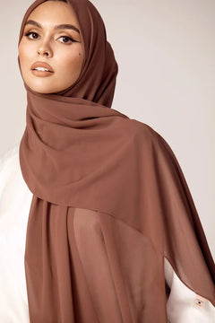 Georgette Hijab Online Pakistan, in cedar color . a women wearing it with white top looking her straight