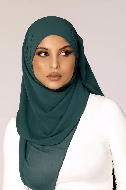 Georgette Hijab Online Pakistan, in Teal color. A woman wearing it with white top looking her left.