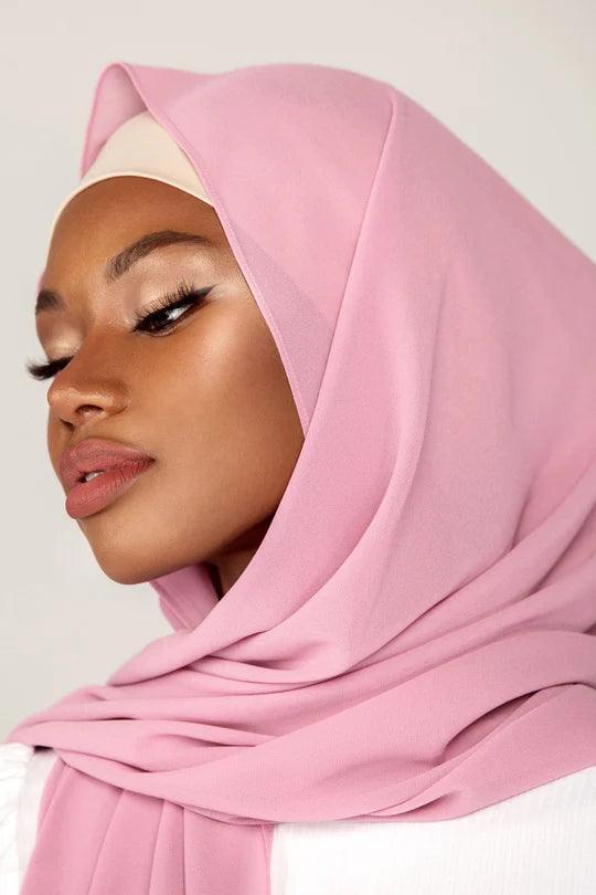 Georgette Hijab Online Pakistan, in French rose color. A woman wearing it with white top looking her right.