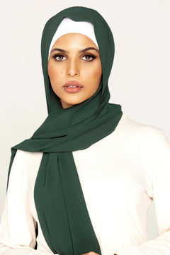 Georgette Hijab Online Pakistan, in emerald green color . a women wearing it with white top looking her straight.