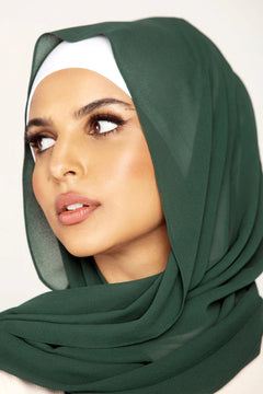 Georgette Hijab Online Pakistan, in emerald green color . a women wearing it with white top looking her right